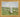 Gabriel Heaton painting of Jesus Christ as the Good Shepherd standing in a green meadow holding a staff with a flock of white sheep in the background