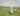 Gabriel Heaton painting of Jesus Christ as the Good Shepherd standing in a green meadow holding a staff with a flock of white sheep in the background