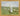 Gabriel Heaton painting of Jesus Christ as the Good Shepherd standing in a green meadow holding a staff with a flock of white sheep in the background