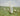 Gabriel Heaton painting of Jesus Christ as the Good Shepherd standing in a green meadow holding a staff with a flock of white sheep in the background